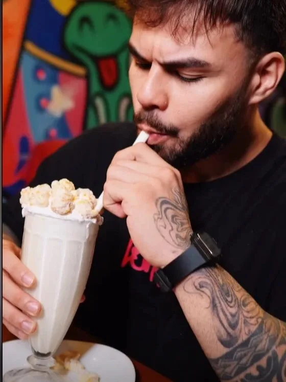 Capa de Reel produzido pela AND: homem tomando milkshake em frente a uma parede grafitada